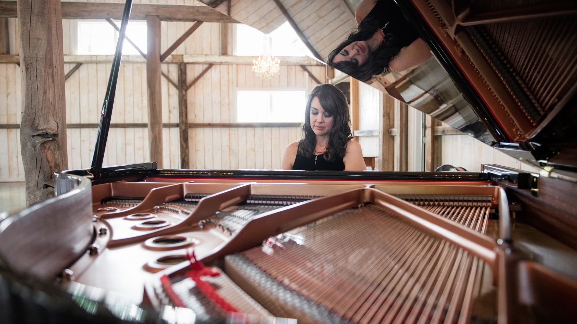 A professional portrait of Kimberley Dunn sitting at a grand piano, capturing her artistry as a singer and pianist.
