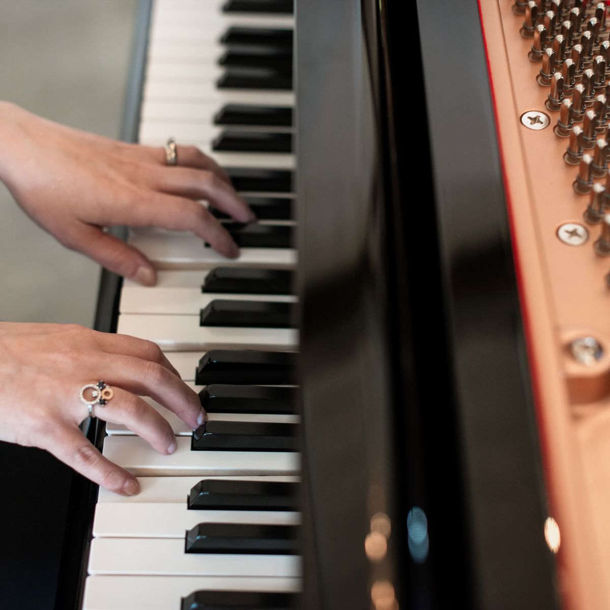 A close-up view of Kimberley Dunn's hands playing piano keys, representing her piano and vocal demos.