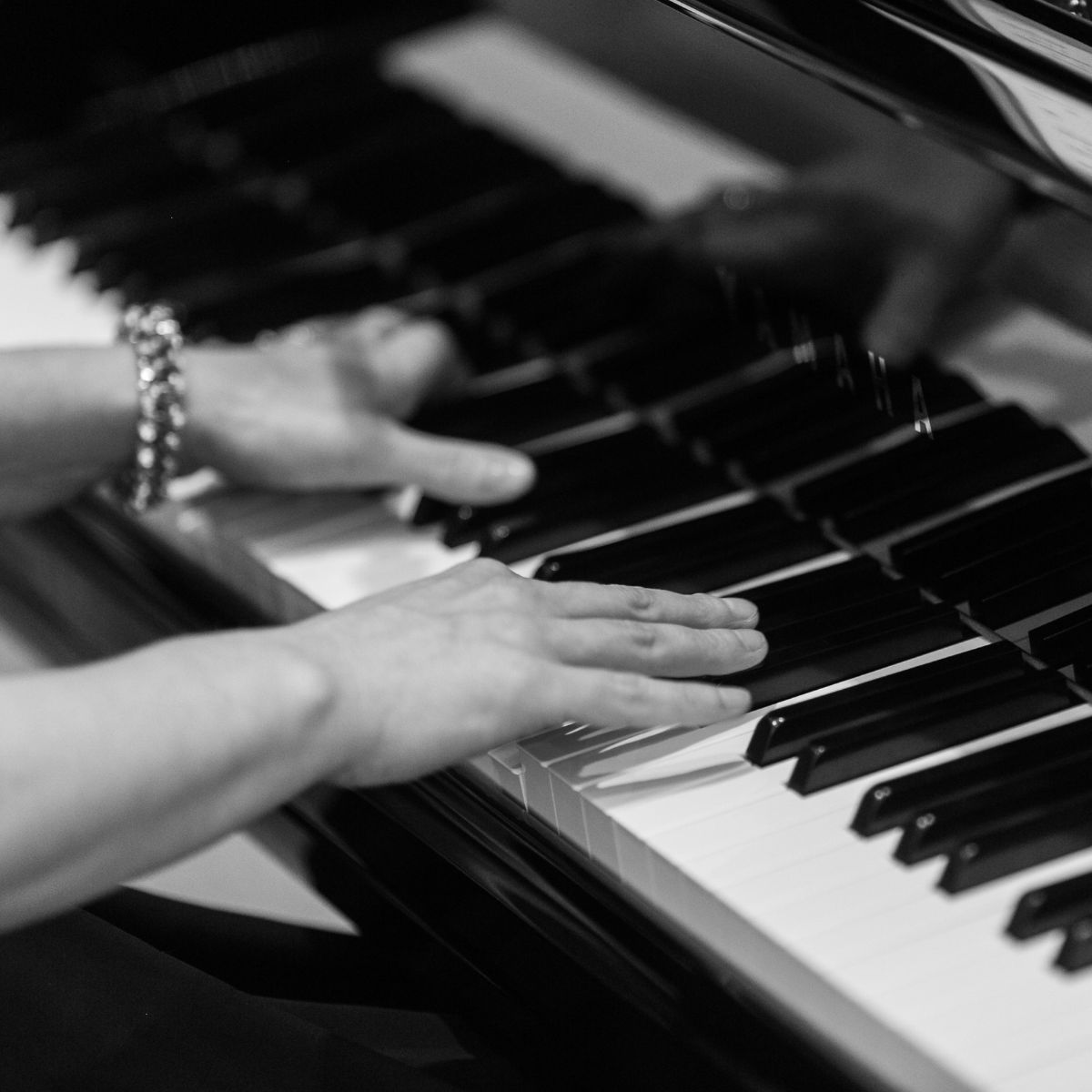 A close up of Kimberley Dunn's hands performing on a Yamaha grand piano.