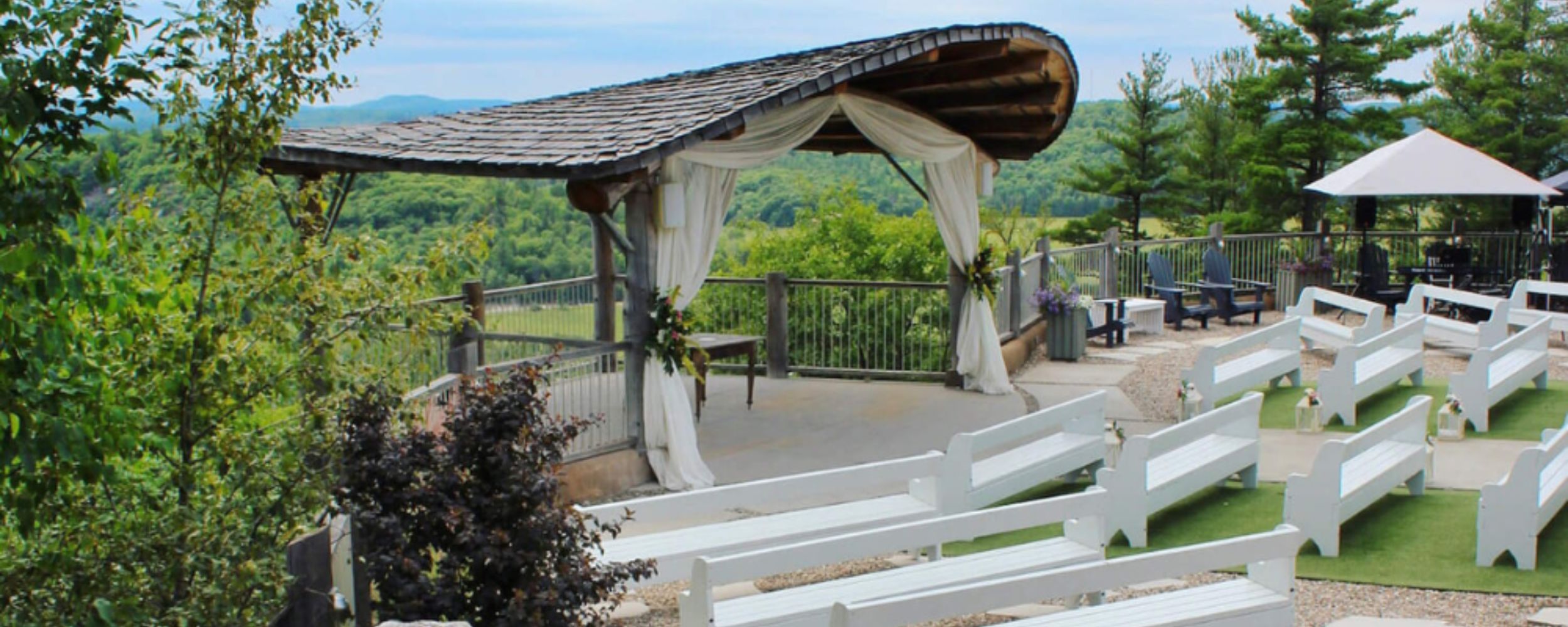 An outdoor cliffside wedding ceremony at Le Belvedere featuring a white canopy for the live music setup.