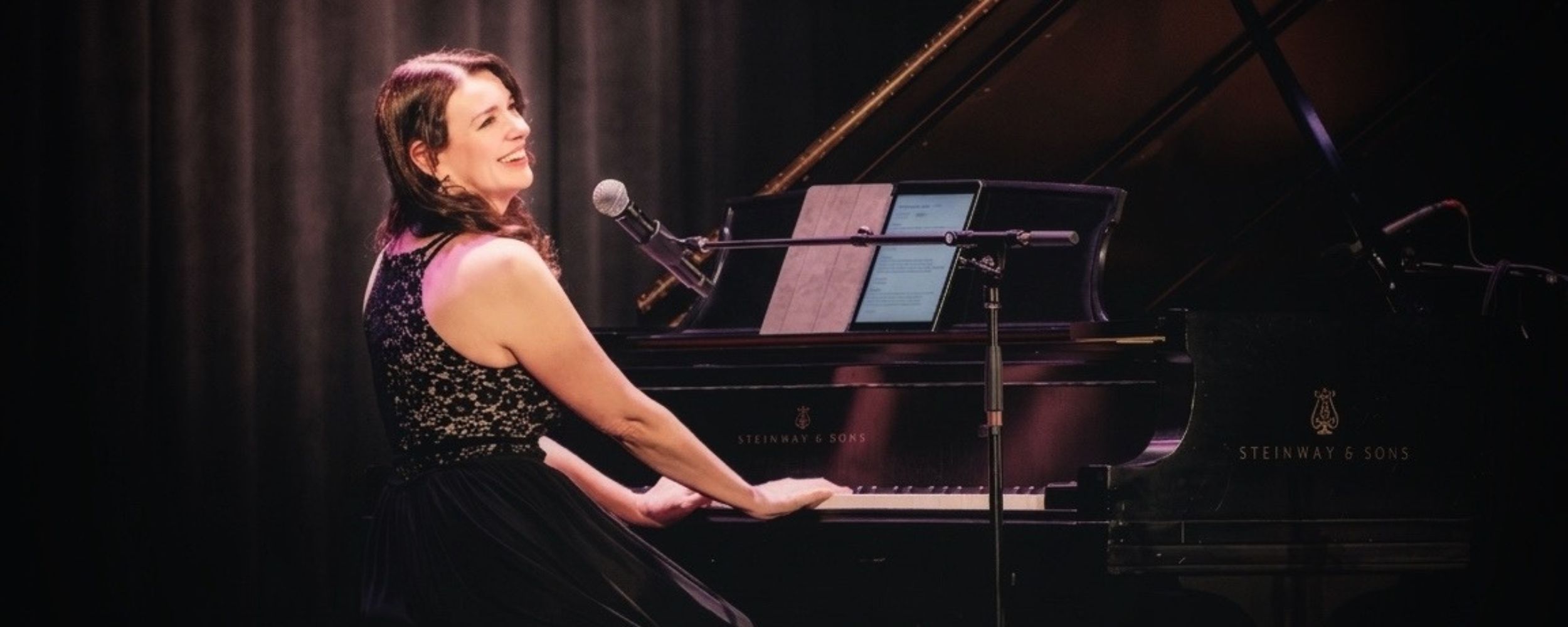 Kimberley Dunn performing on stage at Strong Auditorium for the Bob Dylan Leonard Cohen Tribute Concert at University of Rochester.